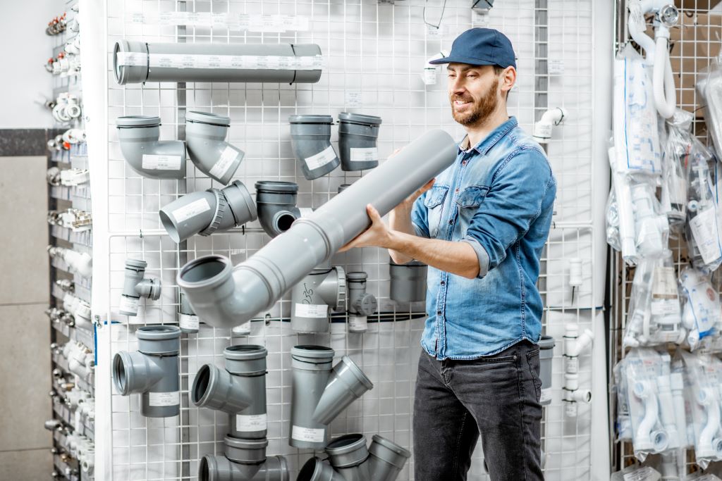 why choose us, man choosing drain pipes in the plumbing shop