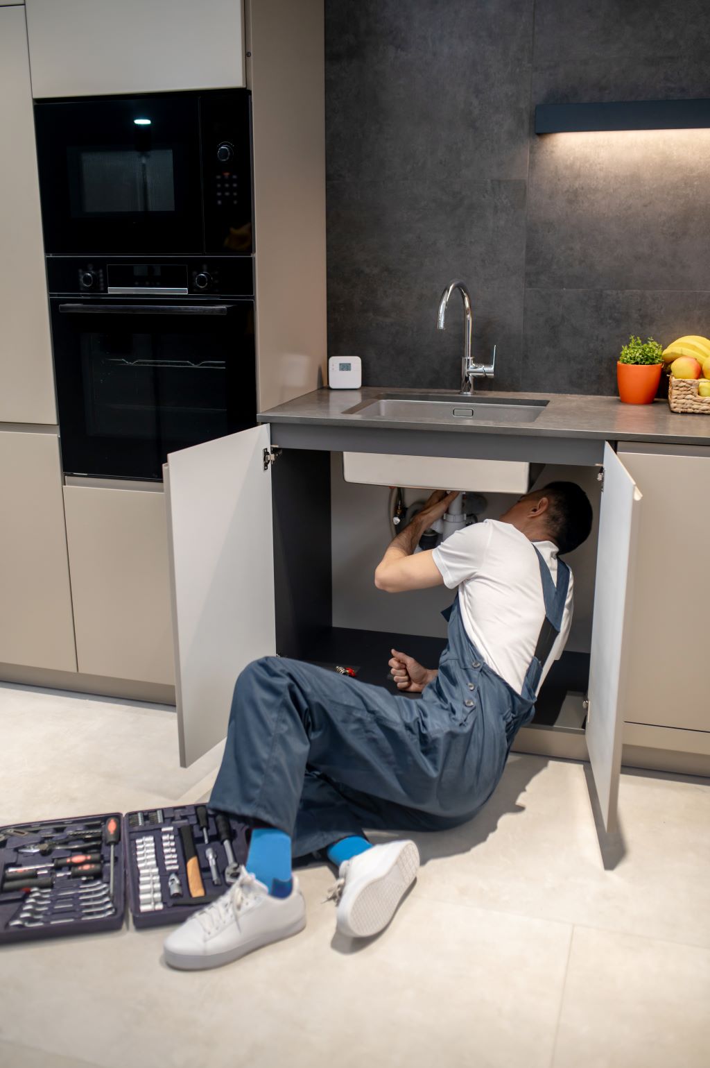 about us, man reclining looking drainage under kitchen sink