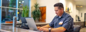 a modern, well-lit office with a sleek desk featuring a laptop open to a website showcasing local plumbing services, while a plumbing technician in a clean uniform discusses emergency drain cleaning solutions over the phone.